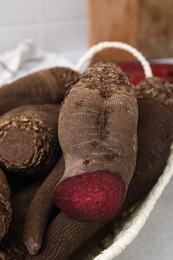 Photo of Whole and cut red beets in basket on table, closeup