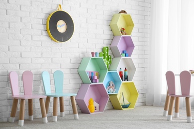 Child room interior with colorful shelves near brick wall