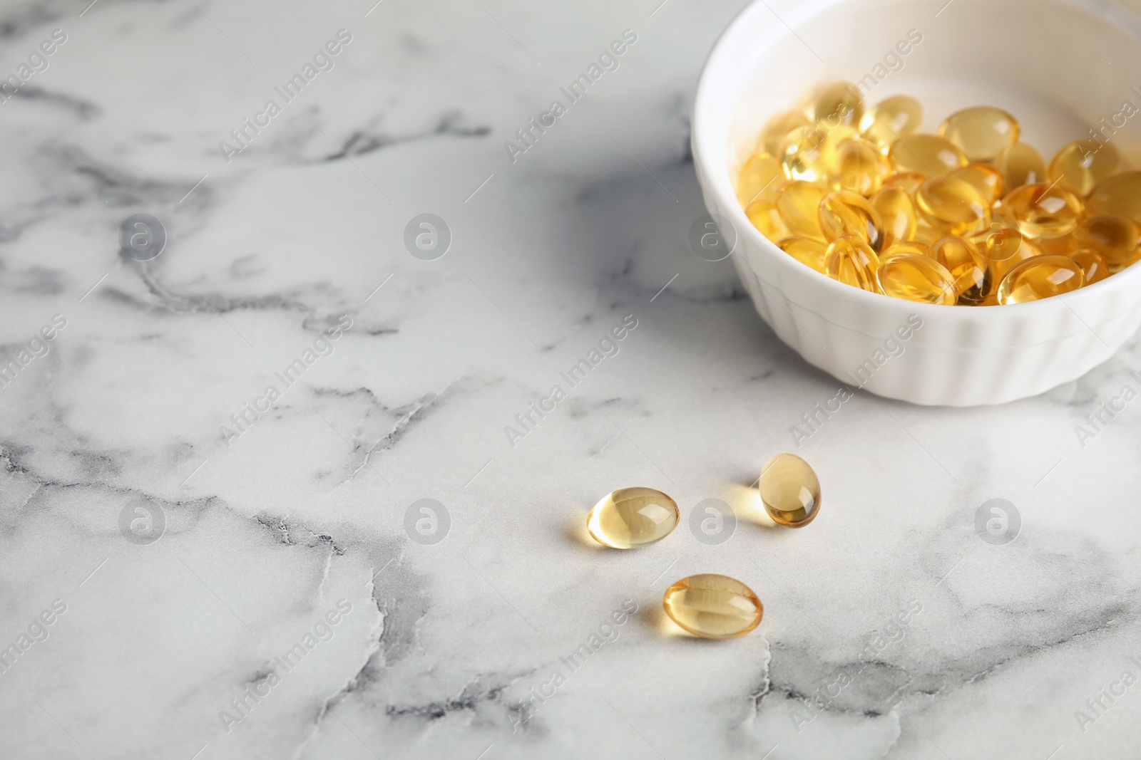 Photo of Bowl with cod liver oil pills and space for text on marble background