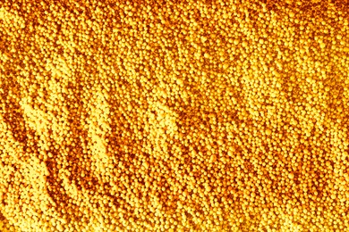 Many golden beads as background, top view