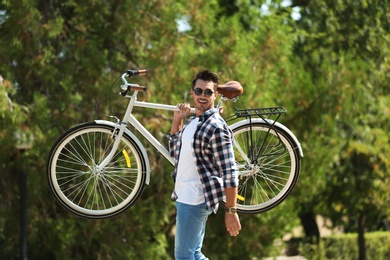 Handsome young hipster man with bicycle in park