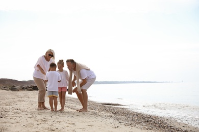 Photo of Cute little children with grandparents on sea beach