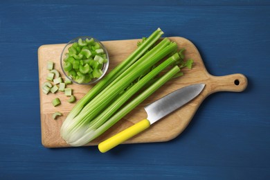 Fresh cut and whole celery on blue wooden table, top view