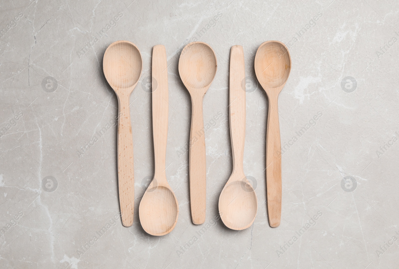 Photo of Wooden spoons on grey table, flat lay. Cooking utensils