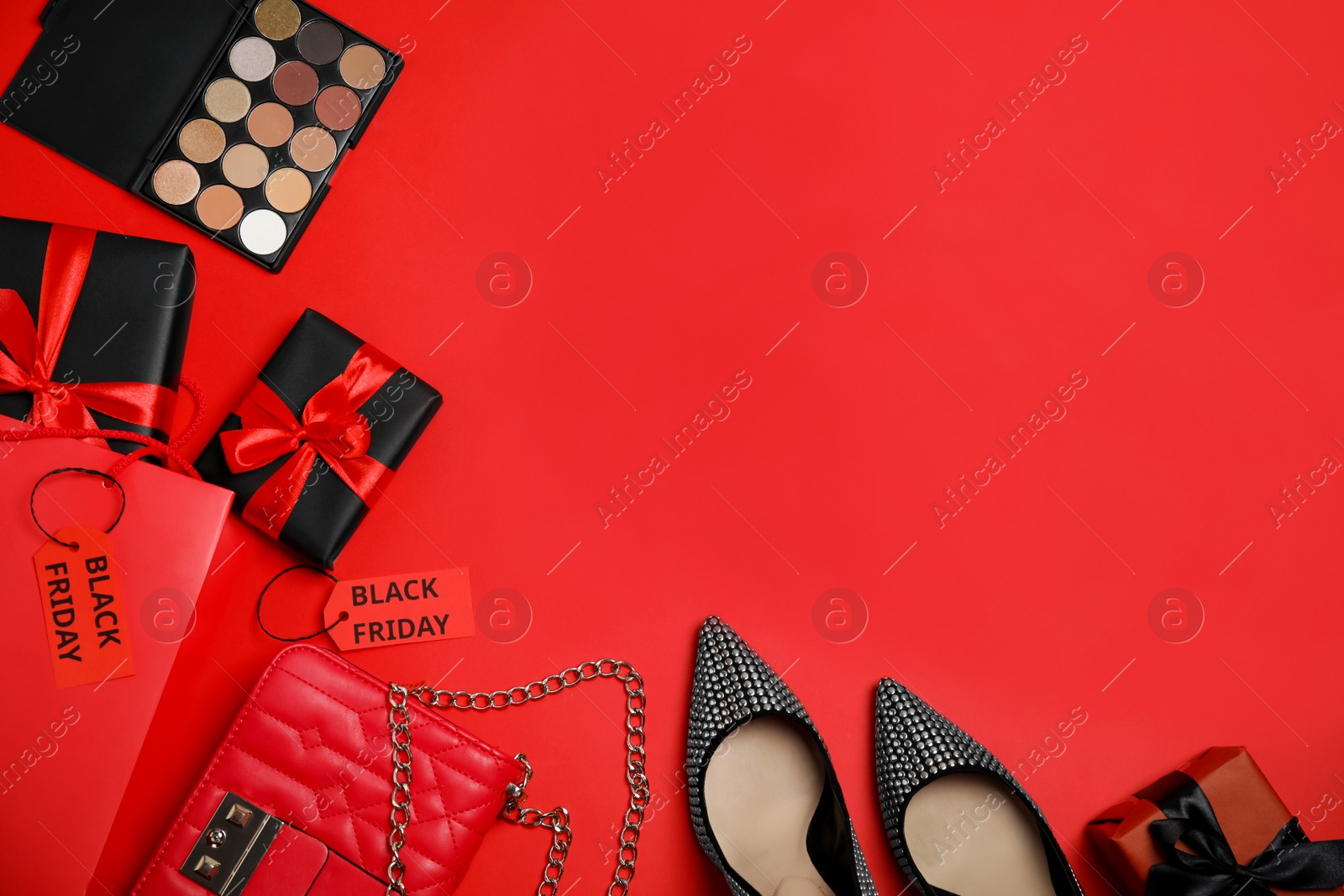 Photo of Gift boxes, cosmetics, shoes, stylish women's accessories and space for text on red background, flat lay. Black Friday sale