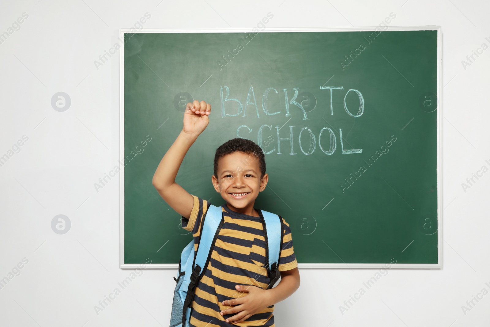 Photo of Little African-American child near chalkboard with text BACK TO SCHOOL