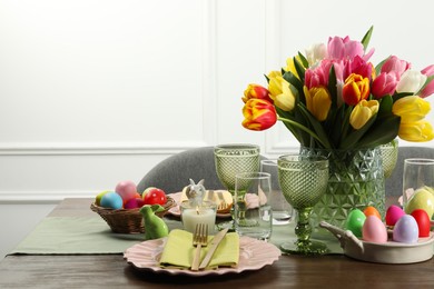 Photo of Easter celebration. Festive table setting with beautiful flowers and painted eggs