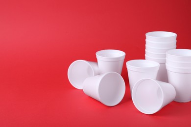 Many white styrofoam cups on red background, space for text