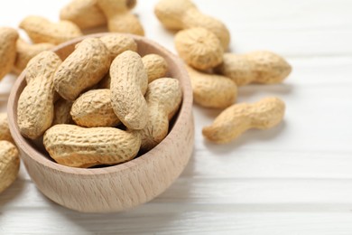 Photo of Fresh peanuts in bowl on white wooden table, closeup