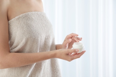 Photo of Young woman holding jar of cream at home, closeup