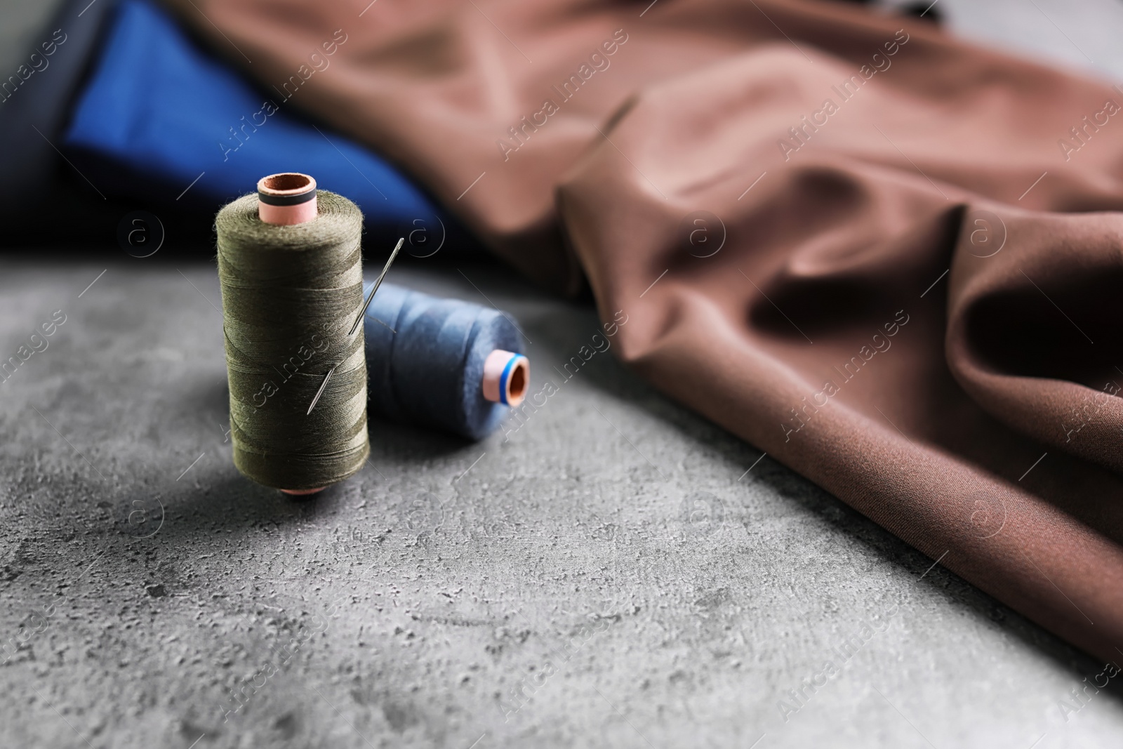 Photo of Threads and needle for tailoring on grey background