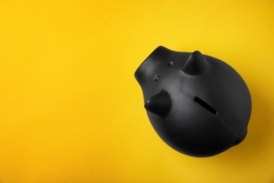 Black piggy bank on color background, top view