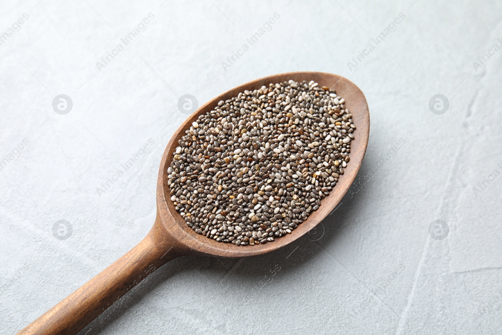 Photo of Spoon with chia seeds on light background, closeup