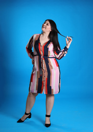 Beautiful overweight woman posing on light blue background. Plus size model