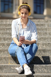 Young woman with headphones listening to music on stairs