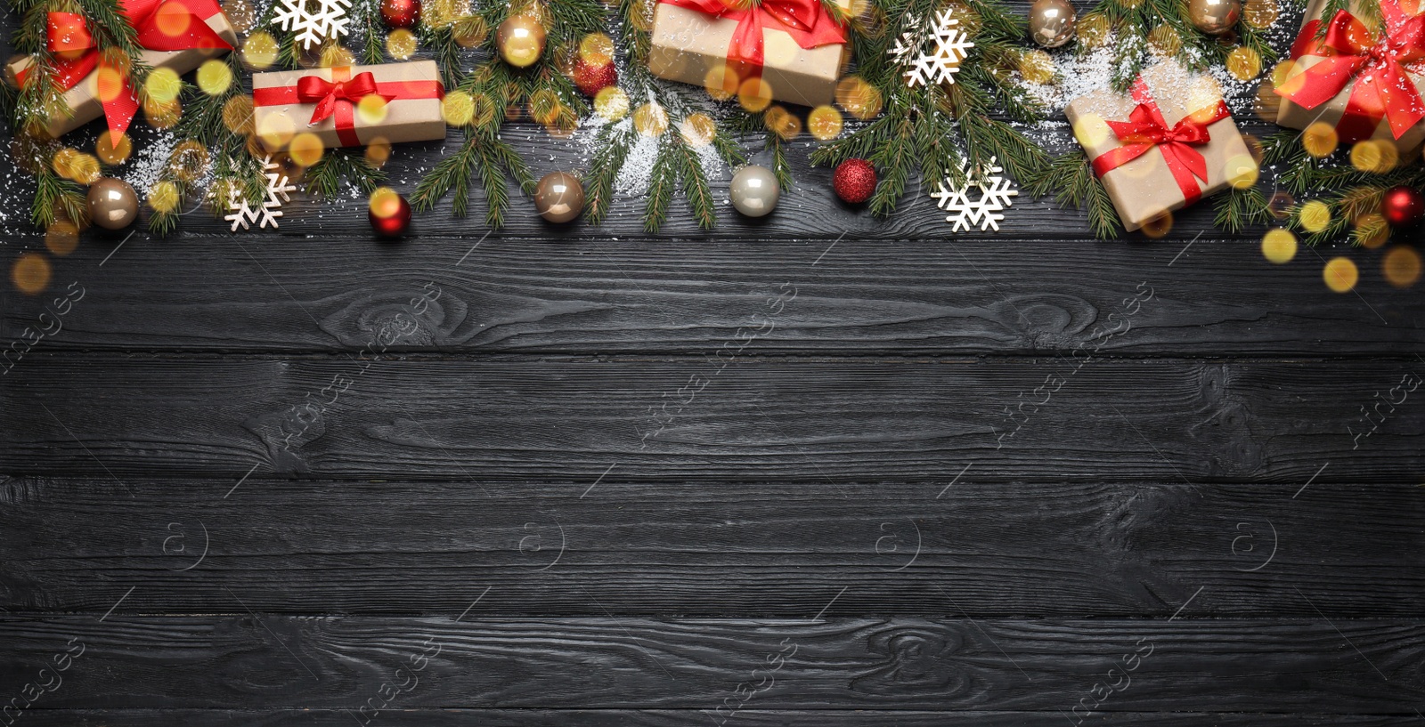 Photo of Christmas greeting card with space for text. Flat lay composition of fir tree branches and festive decor on black wooden background