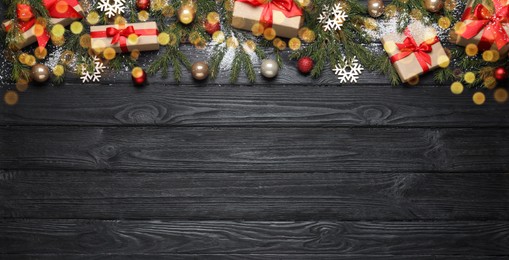 Photo of Christmas greeting card with space for text. Flat lay composition of fir tree branches and festive decor on black wooden background