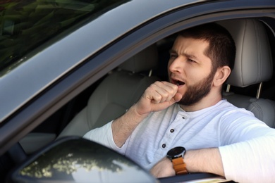 Tired man yawning in his modern car