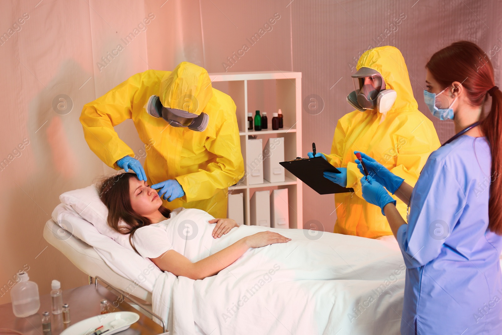 Photo of Professional paramedics examining patient with virus in quarantine ward