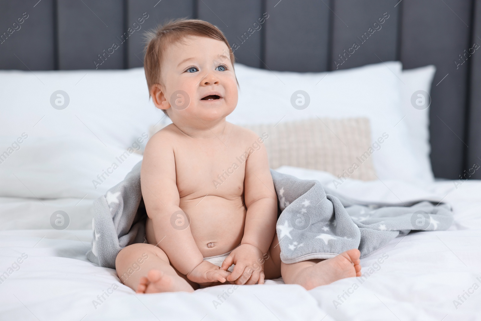 Photo of Cute baby boy sitting on bed at home