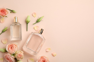Photo of Flat lay composition with different perfume bottles and fresh flowers on beige background, space for text
