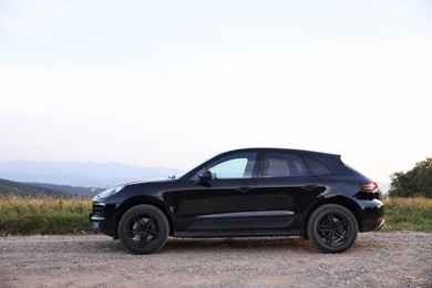 Photo of Modern black car parked on roadside outdoors