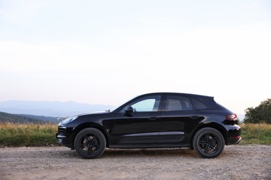 Modern black car parked on roadside outdoors