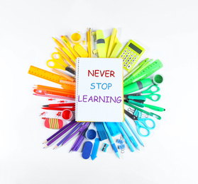 Image of Notebook with phrase NEVER STOP LEARNING and different school stationery on white background, top view