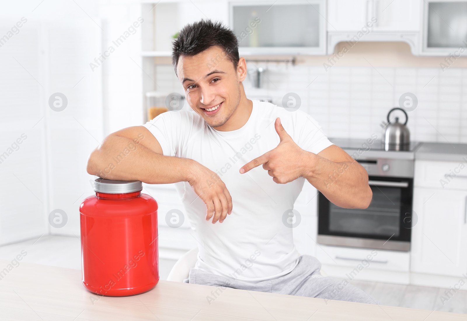 Photo of Man with jar of protein shake powder in kitchen