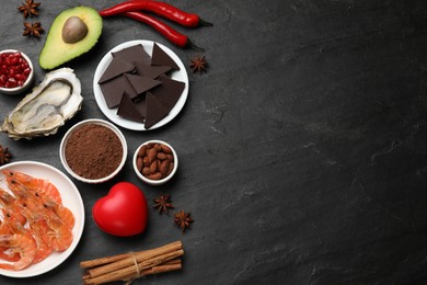 Natural aphrodisiac. Different food products and heart model on black table, flat lay. Space for text