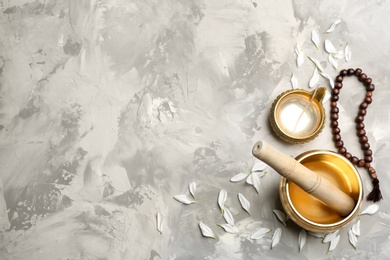 Flat lay composition with golden singing bowl on grey table, space for text. Sound healing