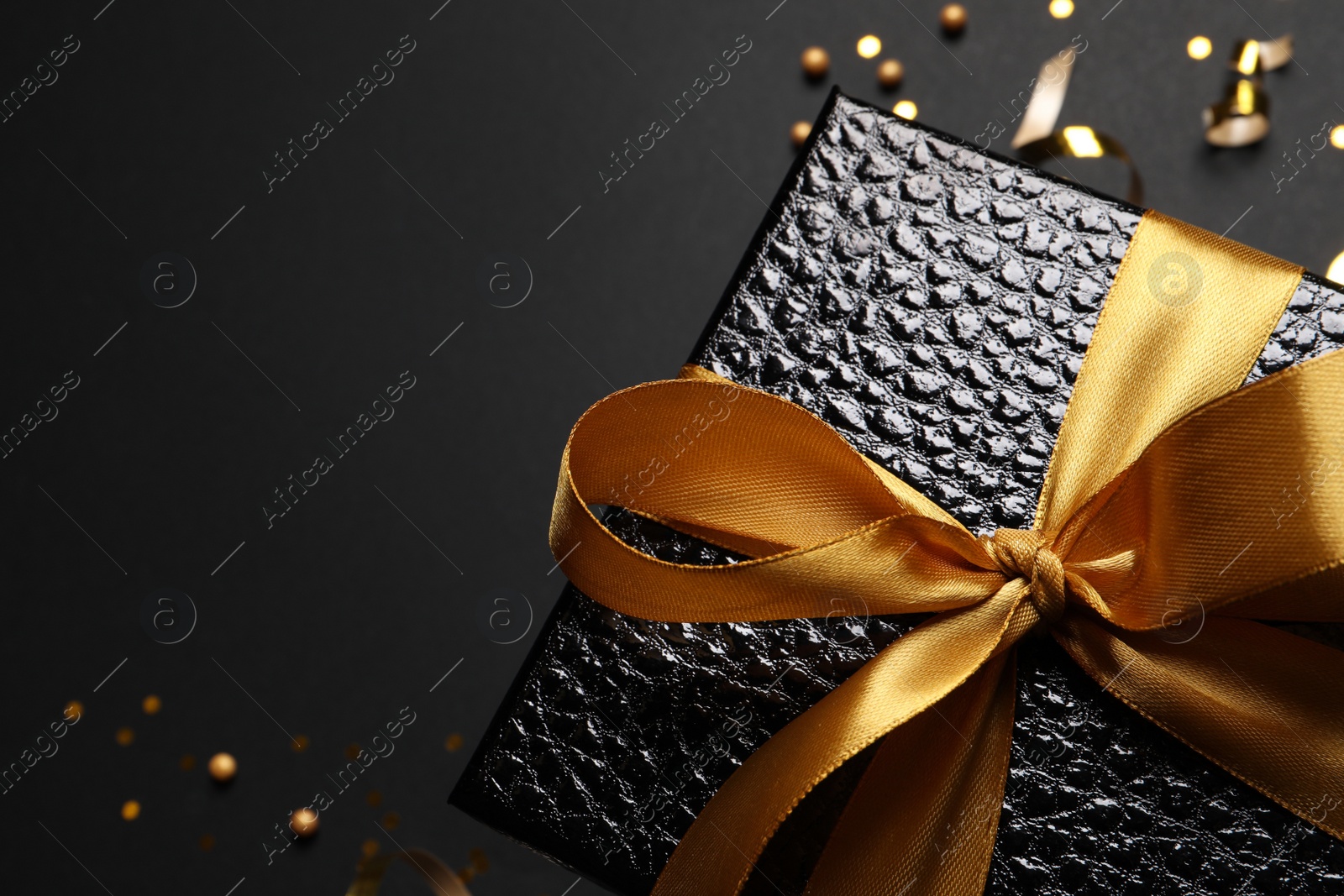 Photo of Gift box and confetti on black background, top view. Space for text