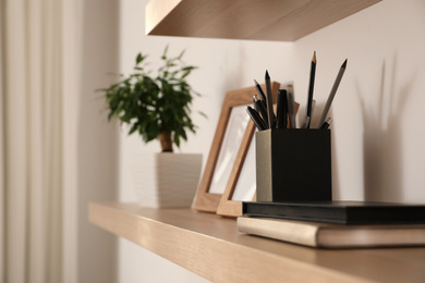 Wooden shelves with books and decorative elements on light wall