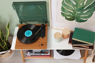 Photo of Stylish turntable with vinyl record console table in room, above view