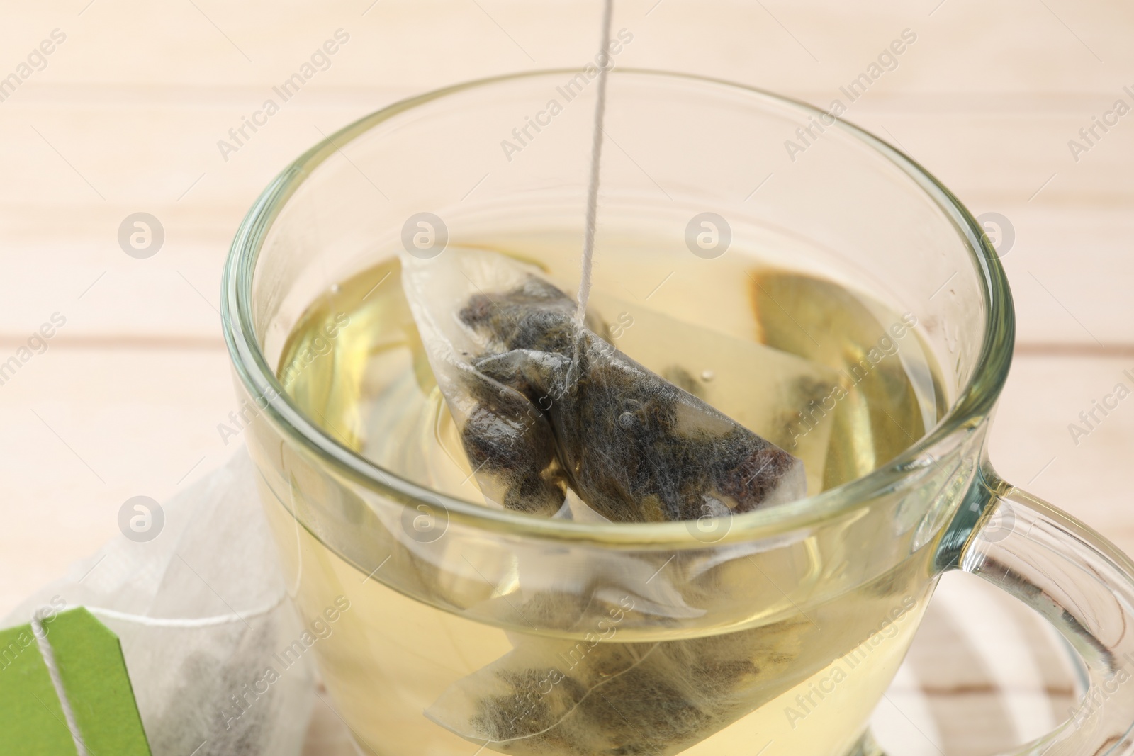Photo of Putting tea bag in glass cup on table, closeup