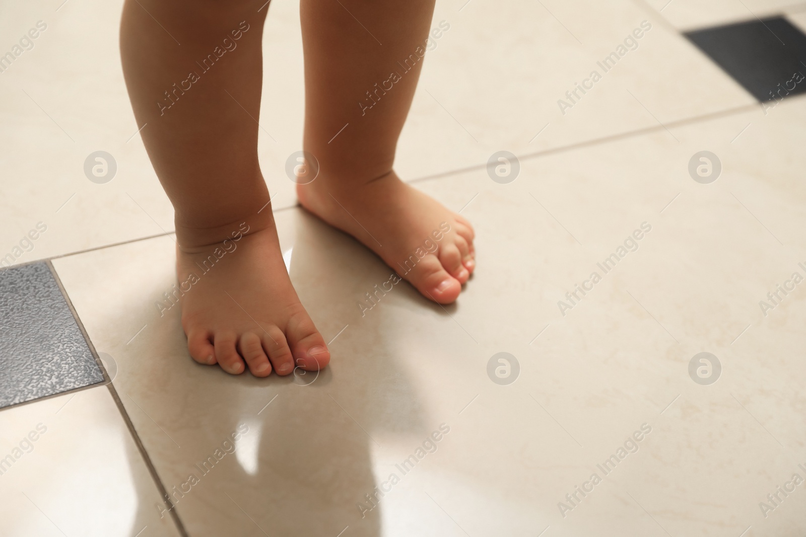 Photo of Cute baby learning to walk indoors, closeup