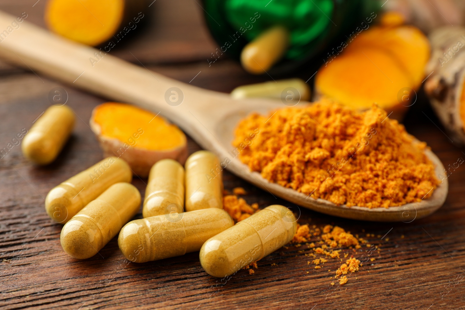 Photo of Aromatic turmeric powder and pills on wooden table, closeup