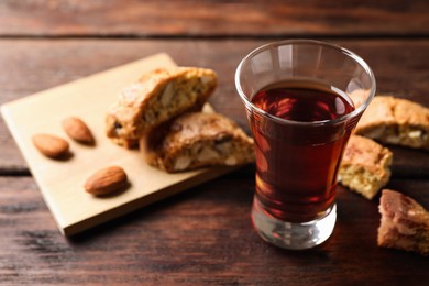 Photo of Tasty cantucci and glass of liqueur on wooden table, space for text. Traditional Italian almond biscuits
