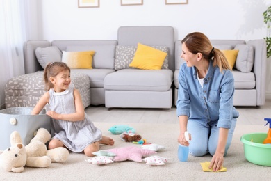 Housewife and daughter cleaning room together