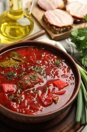 Photo of Stylish brown clay bowl with Ukrainian borsch served on table