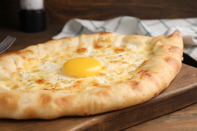 Fresh homemade khachapuri with cheese and egg on wooden table, closeup
