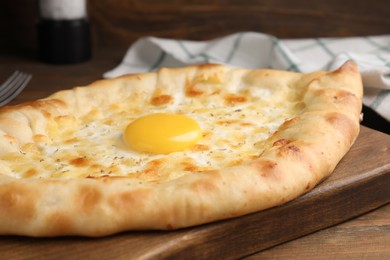 Photo of Fresh homemade khachapuri with cheese and egg on wooden table, closeup