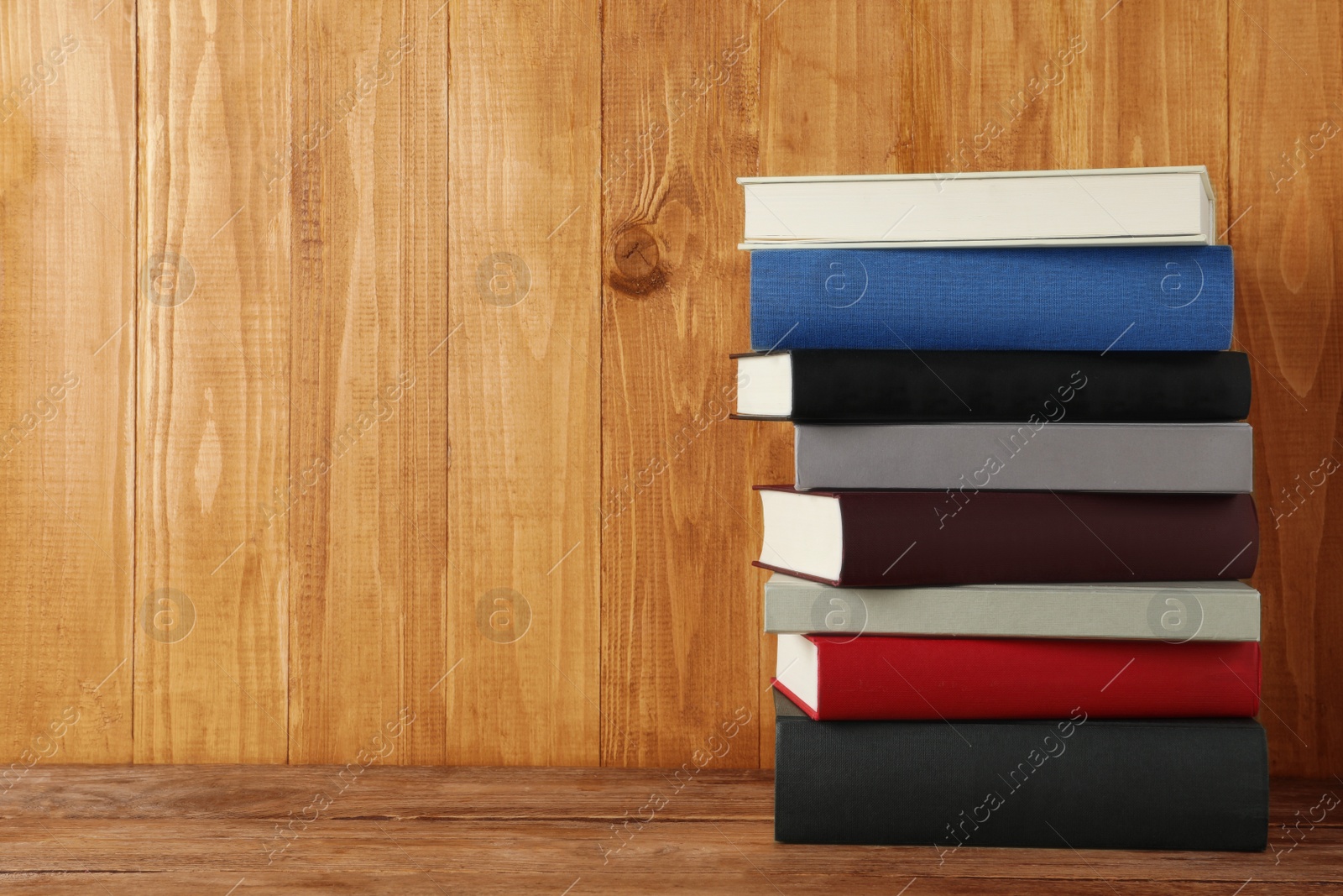 Photo of Stack of hardcover books on wooden table, space for text