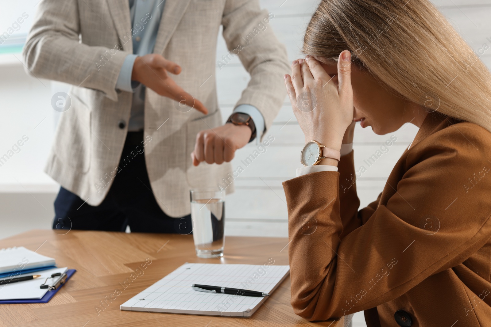 Photo of Businessman pointing on wrist watch while scolding employee for being late in office