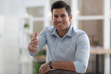 Photo of Businessman reaching out for handshake in office