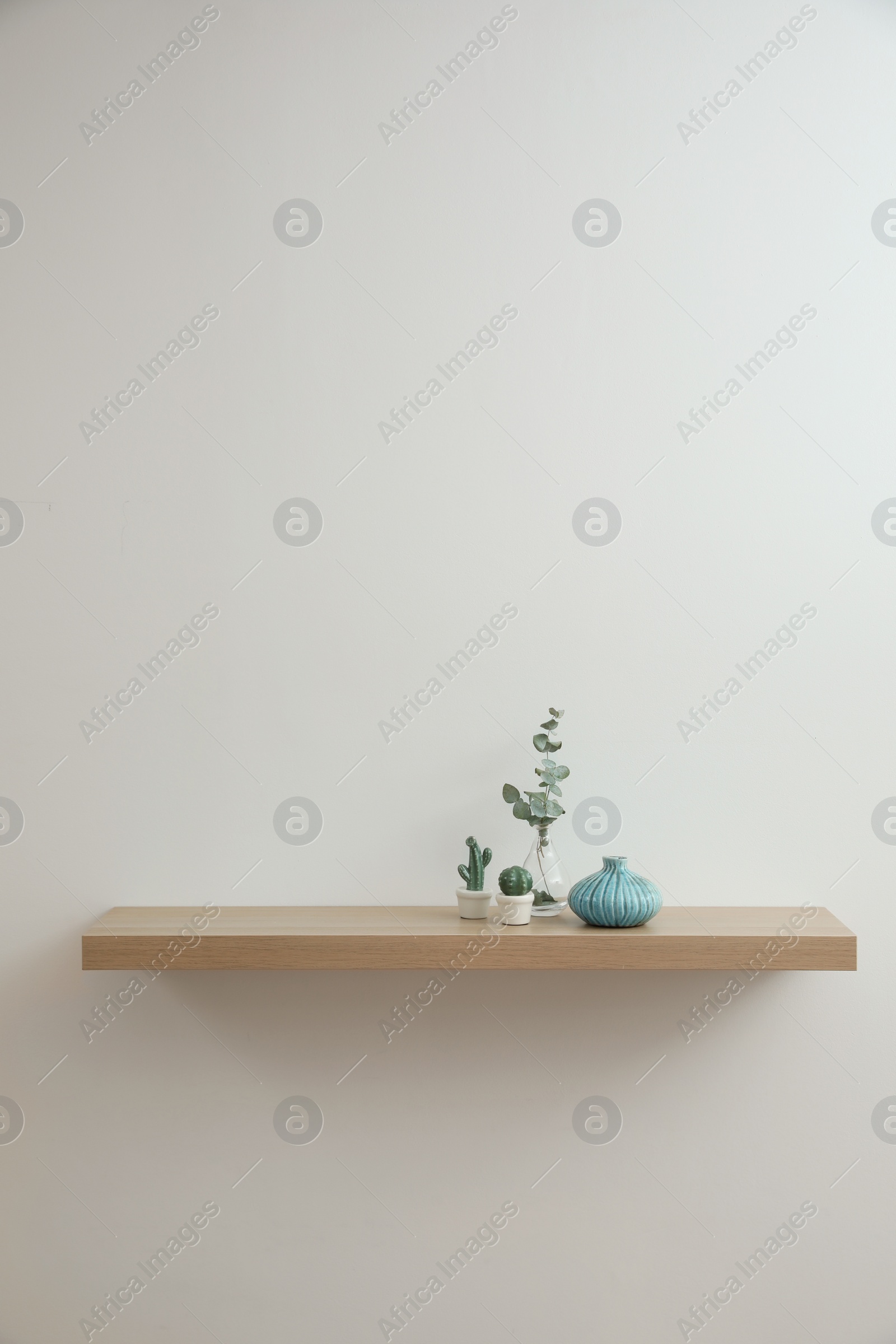 Photo of Wooden shelf with decorative elements on light wall