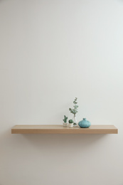 Photo of Wooden shelf with decorative elements on light wall