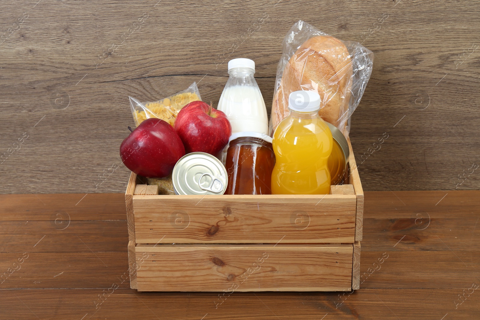 Photo of Humanitarian aid. Different food products for donation in crate on wooden table