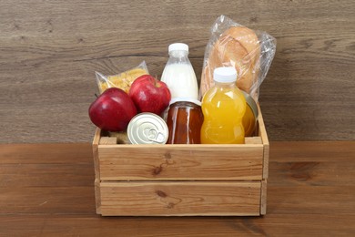 Humanitarian aid. Different food products for donation in crate on wooden table