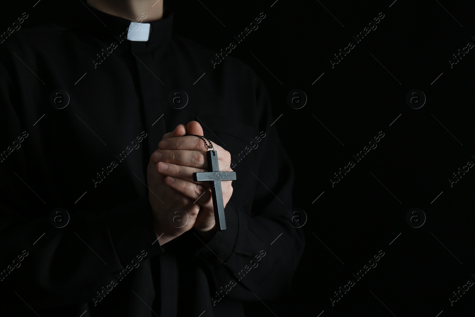 Photo of Priest with cross on dark background, closeup. Space for text